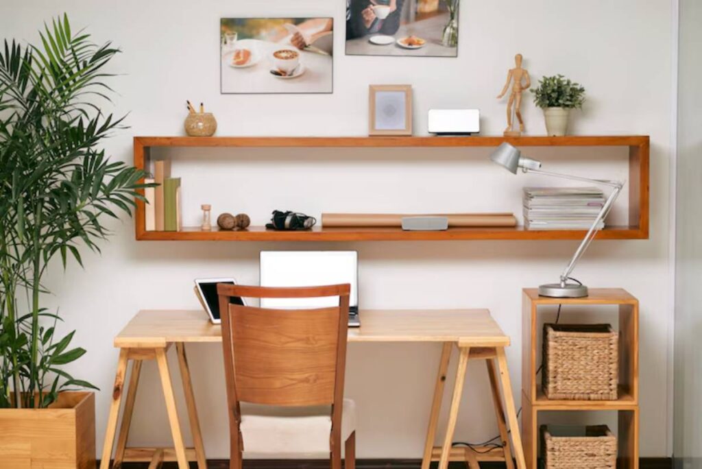 A modern home office setup featuring a wooden desk, laptop, lamp, plants, and decorative shelves with photos and plants.