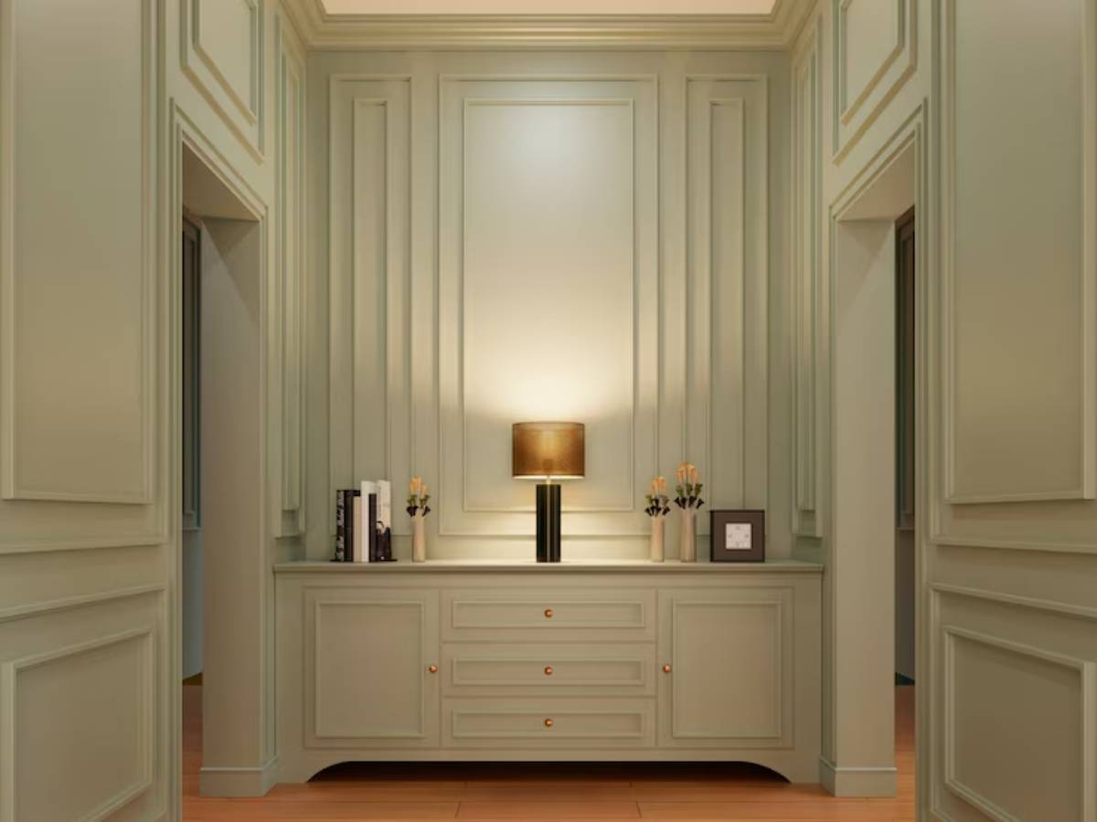 A stylish entryway with green paneled walls, a sleek dresser, a lamp, and decorative flowers, creating a warm and inviting atmosphere. 