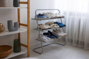 A shoe rack with various types of shoes organized neatly, alongside decorative vases and baskets in a bright, airy room.