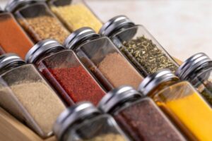 A variety of spice jars neatly arranged in a wooden holder, showcasing colorful spices like paprika, turmeric, and oregano.