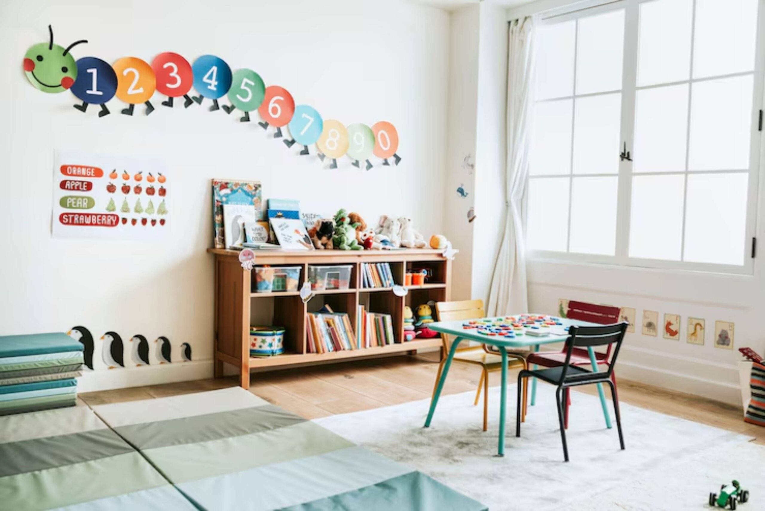 Bright, playful child’s room with a counting caterpillar on the wall, shelves of books, and a colorful activity table.