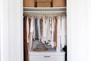 A stylish bedroom and closet featuring organized clothing, shoes, and accessories, with a cozy bed and soft textiles.