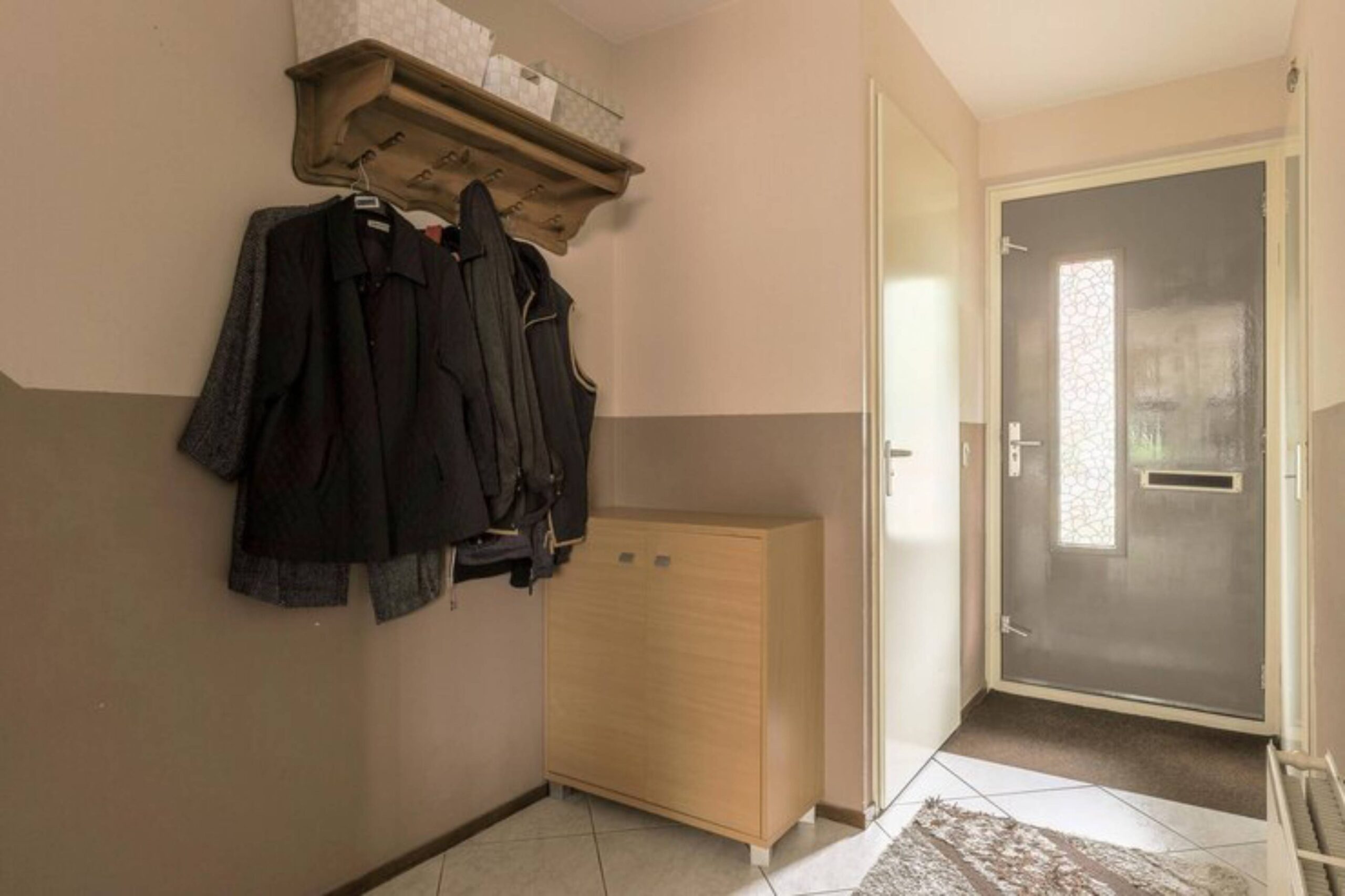 Functional entryway setup in a small apartment with coat hooks, shoe rack, and storage cabinet