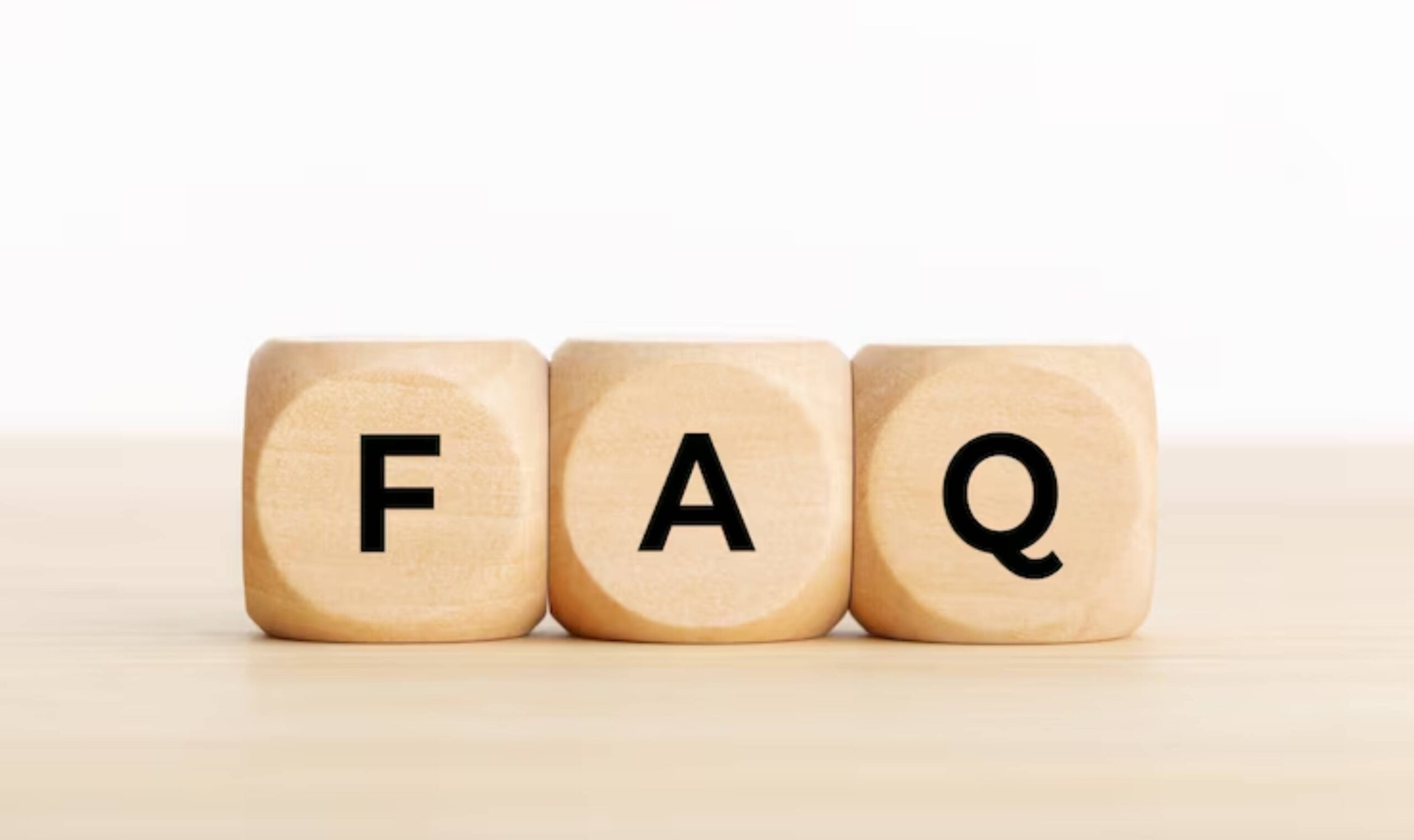 Three wooden blocks arranged to spell FAQ, symbolizing frequently asked questions, on a light-colored surface.