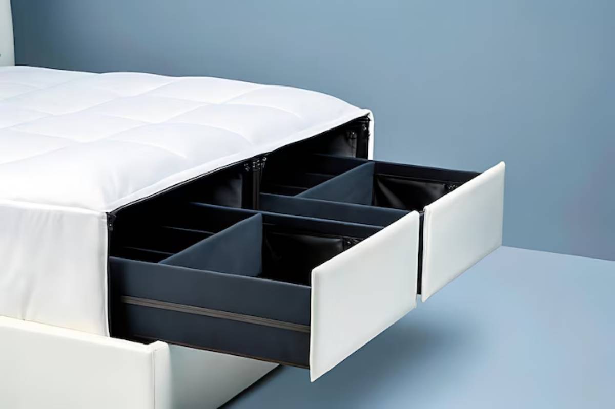 A modern bed with a tufted white mattress and spacious black storage drawers partially open underneath, set against a blue background.
