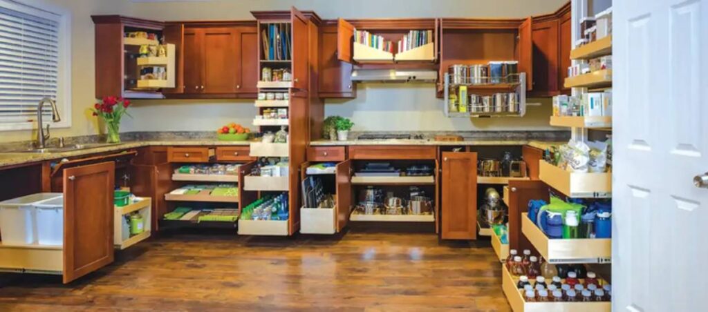 A well-organized kitchen featuring wooden cabinets, open shelves with books and jars, and neatly arranged drawers for utensils and ingredients.